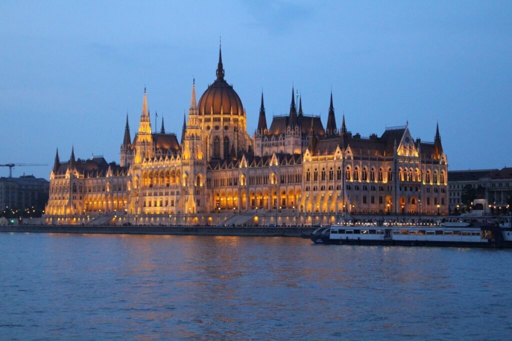 Beleuchtetes ungarisches Parlamentsgebäude am Donauufer in Budapest bei Nacht