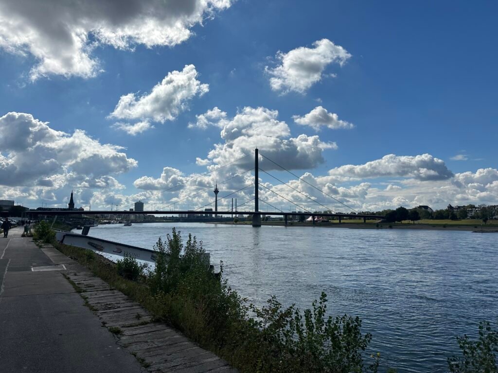 Rhein in Düsseldorf mit Brücke und Rheinufer unter blauem Himmel