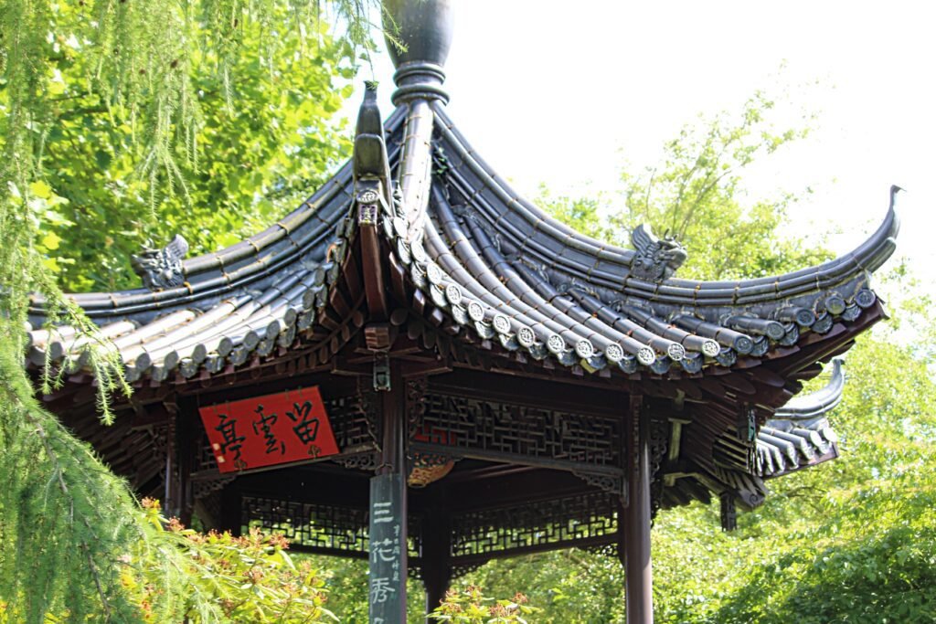Chinesisches Teehaus im Luisenpark Mannheim mit geschwungenem Dach zwischen grünen Bäumen