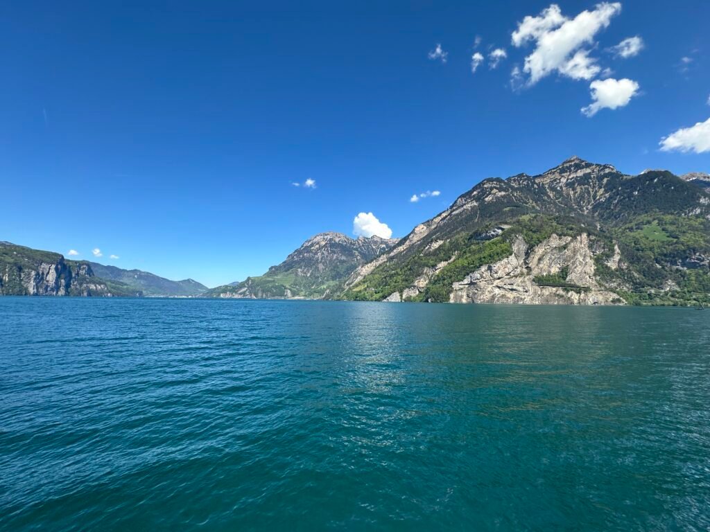 Blauer Vierwaldstättersee mit steilem Berghang unter blauem Himmel